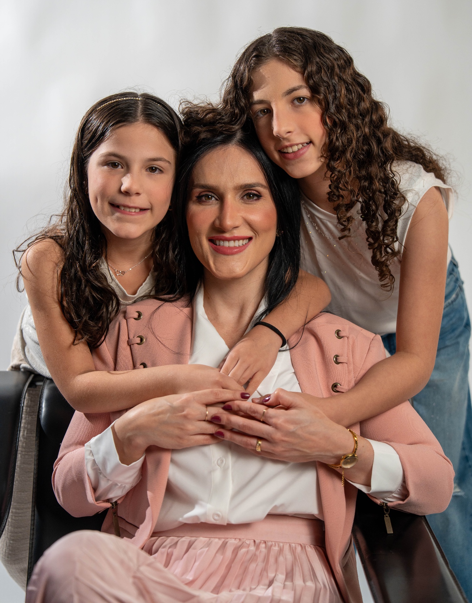 Mãe sorridente abraçada com suas filhas adolescentes estudando